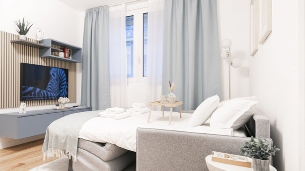 Ein modernes Schlafzimmer mit Bett, Nachttisch und Fernseher an einer Wandhalterung.