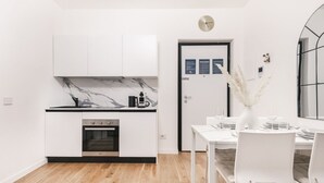 Eine moderne Küche mit weißen Schränken, einer Marmor-Spritzschutzleiste und einem eingebauten Backofen.