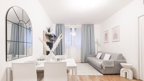 Ein modernes Wohnzimmer mit Essbereich, einem grauen Sofa und einem weißen Tisch, gedeckt für vier Personen.