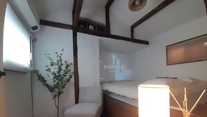A compact room with a bed, a bedside table with a lamp, a small chair, and a potted plant. - Hyehwa 1937 (Hanok), a traditional Korean house built in 1937 (Seongbuk District)