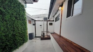 A narrow corridor with a wooden bench on the right, a green wall on the left, and a small table with items in the center. - Hyehwa 1937 (Hanok), a traditional Korean house built in 1937 (Seongbuk District)
