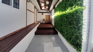 A narrow hallway with a wooden bench, a staircase, and a green vertical garden wall. - Hyehwa 1937 (Hanok), a traditional Korean house built in 1937 (Seongbuk District)
