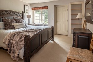 A bedroom with a large bed, a wooden dresser, a chair, and a door. - Fairway Views | Hot Tub | Fireplace (Big Sky)