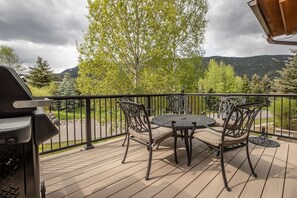 A wooden deck with a round table and chairs, surrounded by a metal railing. - Fairway Views | Hot Tub | Fireplace (Big Sky)