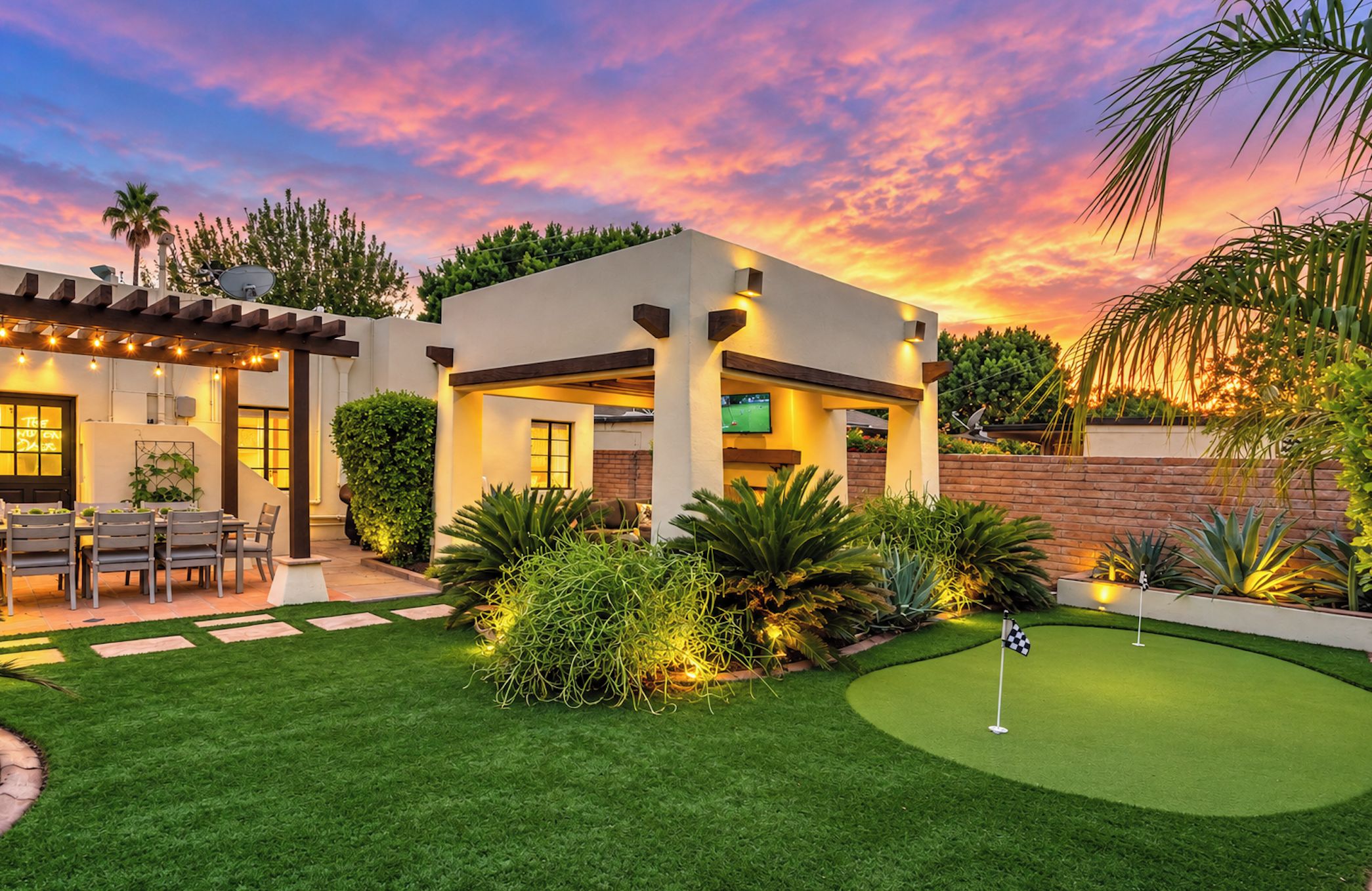 Una casa moderna con césped bien cuidado y un campo de práctica de golf.
