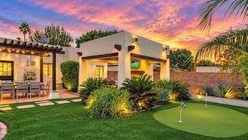 Una casa moderna con césped bien cuidado y un campo de práctica de golf.