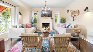 A spacious living room with a fireplace, two sofas, a coffee table, and wicker chairs. - Timeless Elegance: Historic Estate w/ Pool, Hot Tub + Putting Green (Phoenix)