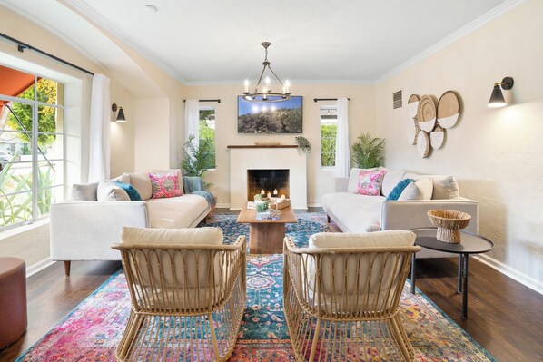 A spacious living room with a fireplace, two sofas, a coffee table, and wicker chairs. - Timeless Elegance: Historic Estate w/ Pool, Hot Tub + Putting Green (Phoenix)