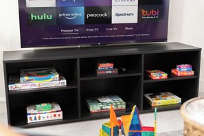 A TV displaying various streaming services and a shelf with board games. - Timeless Elegance: Historic Estate w/ Pool, Hot Tub + Putting Green (Phoenix)