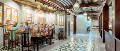 Un restaurante con mesas y sillas de madera, suelo con diseño y faroles colgantes.