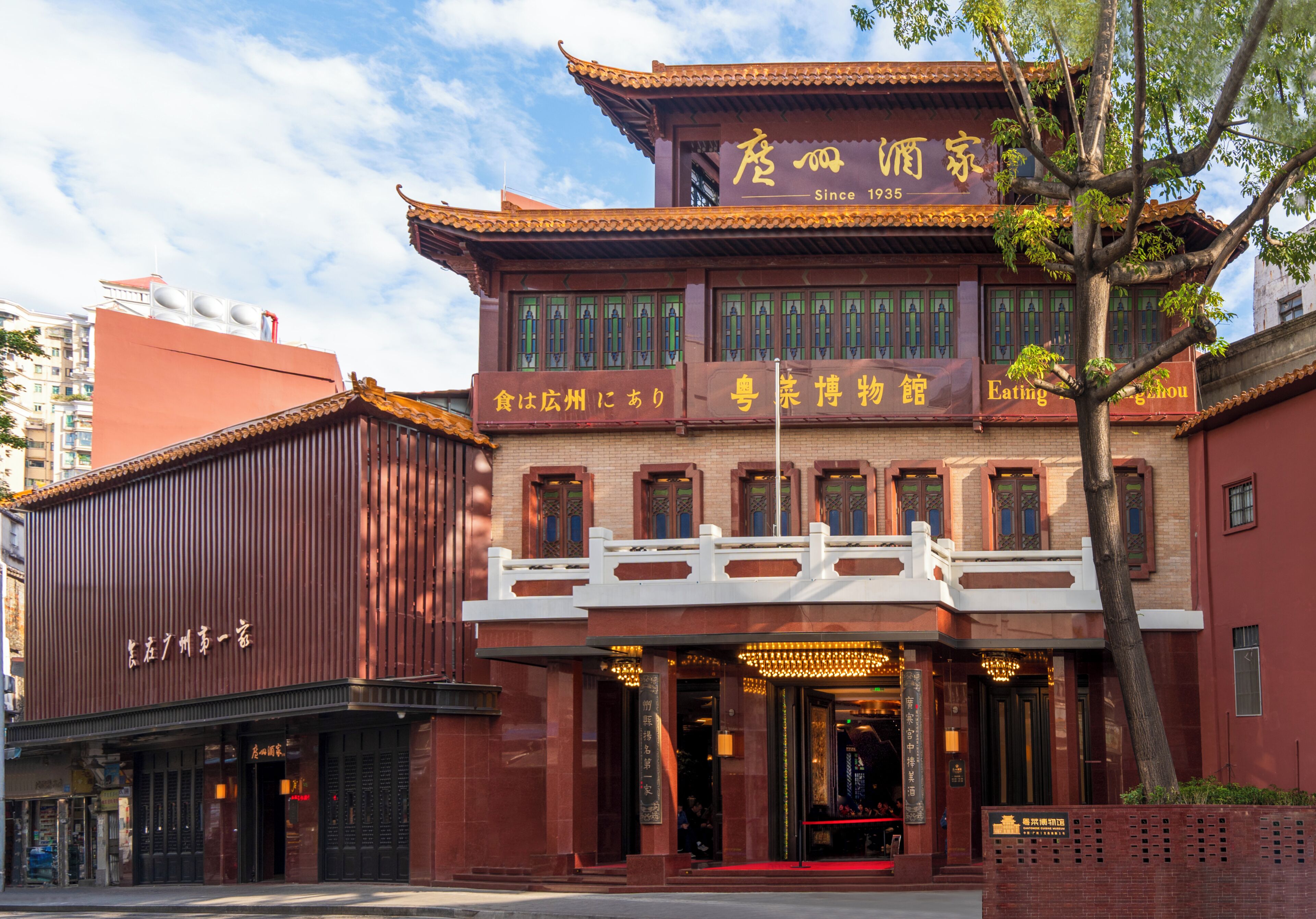 A traditional building with a red facade, a white balcony, and a sign indicating it has been established since 1935.