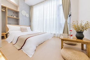 Ein ordentlich eingerichtetes Schlafzimmer mit einem Bett, einem Nachttisch und einem kleinen Tisch mit einer Vase.