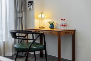 A wooden desk with a lamp, a vase with flowers, and two water bottles. - Stargazing Platform Inn - Heart of Old Canton (Guangzhou)