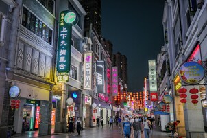 A bustling urban street at night with illuminated signage and traditional lanterns.
