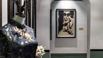 Una fotografía en blanco y negro en un marco colgada en una pared, un jarrón decorativo con flores, y una zona con azulejos verdes.