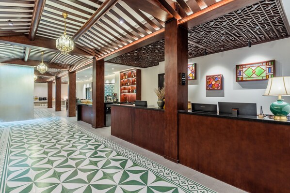 A reception area with a patterned floor, wooden reception desk, and a decorative ceiling. - Stargazing Platform Inn - Heart of Old Canton (Guangzhou)