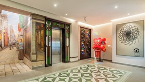 A hotel lobby with a patterned carpet, a traditional elevator, a red lion statue, and a wall with a circular design. - Stargazing Platform Inn - Heart of Old Canton (Guangzhou)