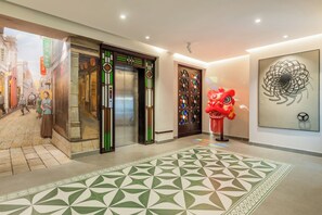 A hotel lobby with a patterned carpet, a traditional elevator, a red lion statue, and a wall with a circular design. - Stargazing Platform Inn - Heart of Old Canton (Guangzhou)