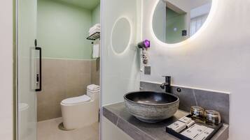 Un baño moderno con un espejo redondo, un lavabo tipo tazón y un inodoro.