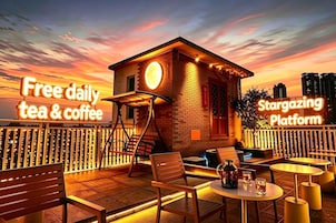 Zona relax sul tetto con un cartello che offre tè e caffè gratuiti ogni giorno, e un altro cartello che pubblicizza una piattaforma per l'osservazione delle stelle.