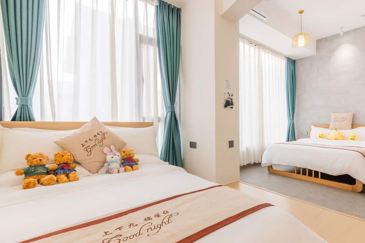 A hotel room with a large bed, a smaller bed, and a wardrobe.