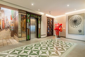 A hotel lobby with a traditional elevator, a red lion dance figure, and a modern art piece. - Stargazing Platform Inn - Heart of Old Canton (Guangzhou)