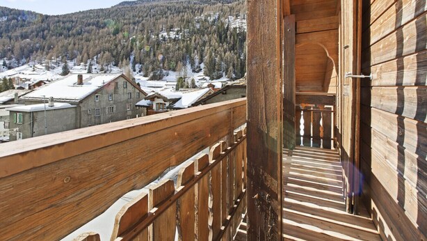 A wooden balcony with a view of a snow-covered village and mountains. - Beautiful alpine apartment 5 minutes from Saas-Fee (Saas-Grund)