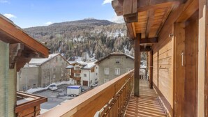 Un balcon en bois offrant une vue sur la ville et les montagnes.