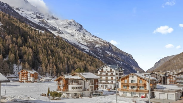 Une station de montagne avec des bâtiments de style chalet, un paysage enneigé et un ciel dégagé.