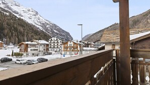 Une station de montagne avec des bâtiments de style chalet, un parking et une vue sur des montagnes enneigées.