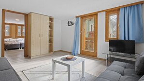 Un salon moderne comprenant un canapé, un téléviseur, une table basse et une armoire.