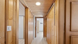 Un couloir en bois, doté d’un plancher de couleur claire, de murs en bois et d’un plafond dans lequel est encastré un luminaire.