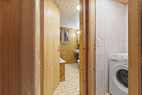 Un baño pequeño con lavadora, lavamanos y retrete.