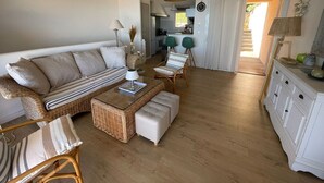 Una sala de estar con un sofá, otomanas, una mesa de centro y sillas.