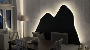 A dining area with a table, chairs, a lamp, and a wall-mounted light fixture.