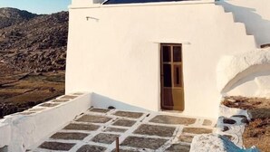 A white church with a bell tower and a dark roof, set against a mountainous backdrop.