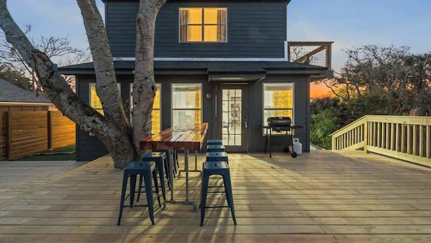 Een tweelaags huis met een terras, een eettafel en stoelen.