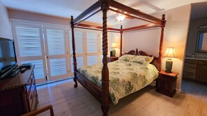 A four-poster bed with a floral bedspread, bedside lamps, and a wooden nightstand.