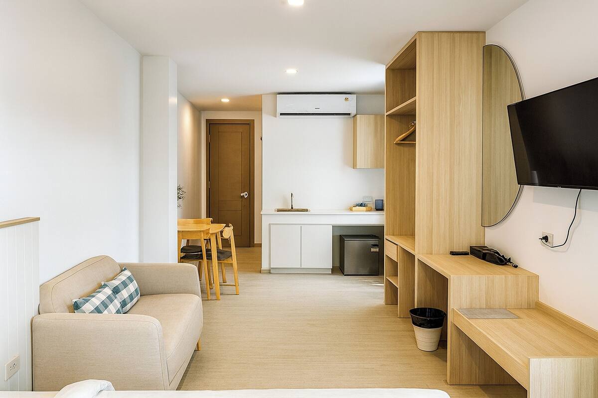 Un espacio habitable compacto con kitchenette, televisor de pantalla plana, sofá y comedor.
