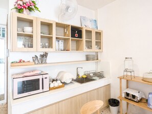Una cocina compacta con microondas, pileta y alacenas.