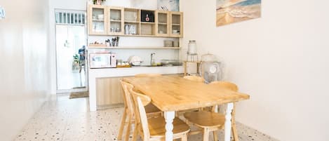 Una cocina con una mesa y sillas de madera, un microondas y un lavabo.