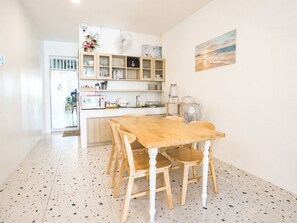 Una cocina con una mesa y sillas de madera, un microondas y un lavabo.