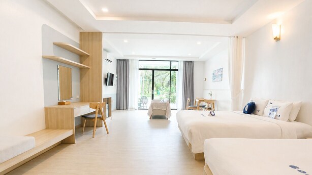 Ein Hotelzimmer mit einem Bett, einem Schreibtisch, einem Sessel, einem kleinen Tisch und einem Fernseher.