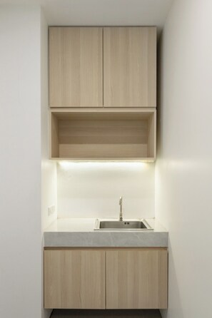 Una cocina con pileta integrada, armarios de madera e iluminación debajo de los alacenas.