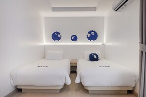 Una habitación de hotel con dos camas, aire acondicionado de pared y una lámpara en el techo.