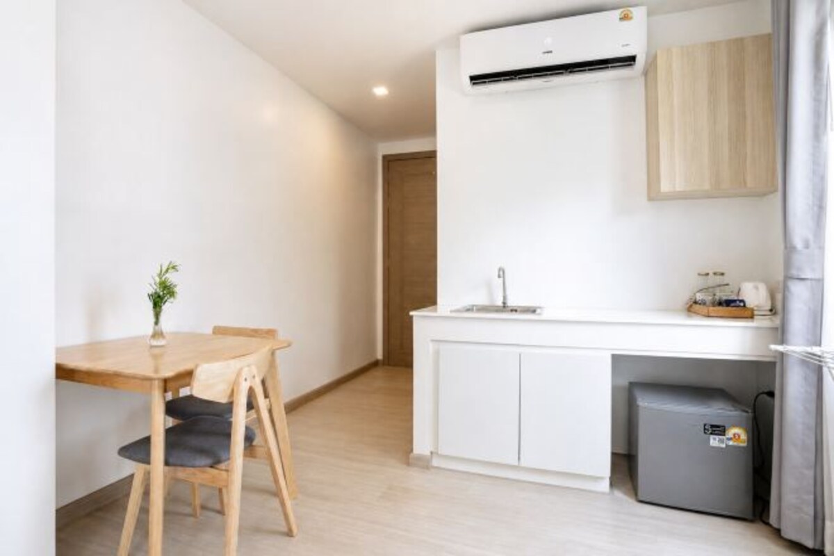Una cocina compacta con mostrador blanco, un lavamanos y un refrigerador pequeño.