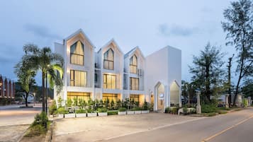 Ein modernes Hotel mit einer symmetrischen Fassade, großen Fenstern und einem gepflegten Garten.