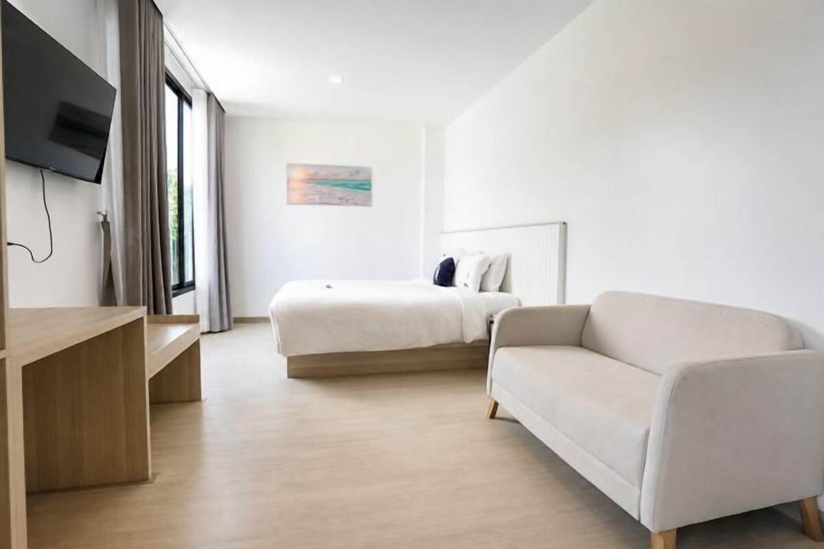 Una habitación de hotel moderna con cama, sofá, televisión y escritorio.