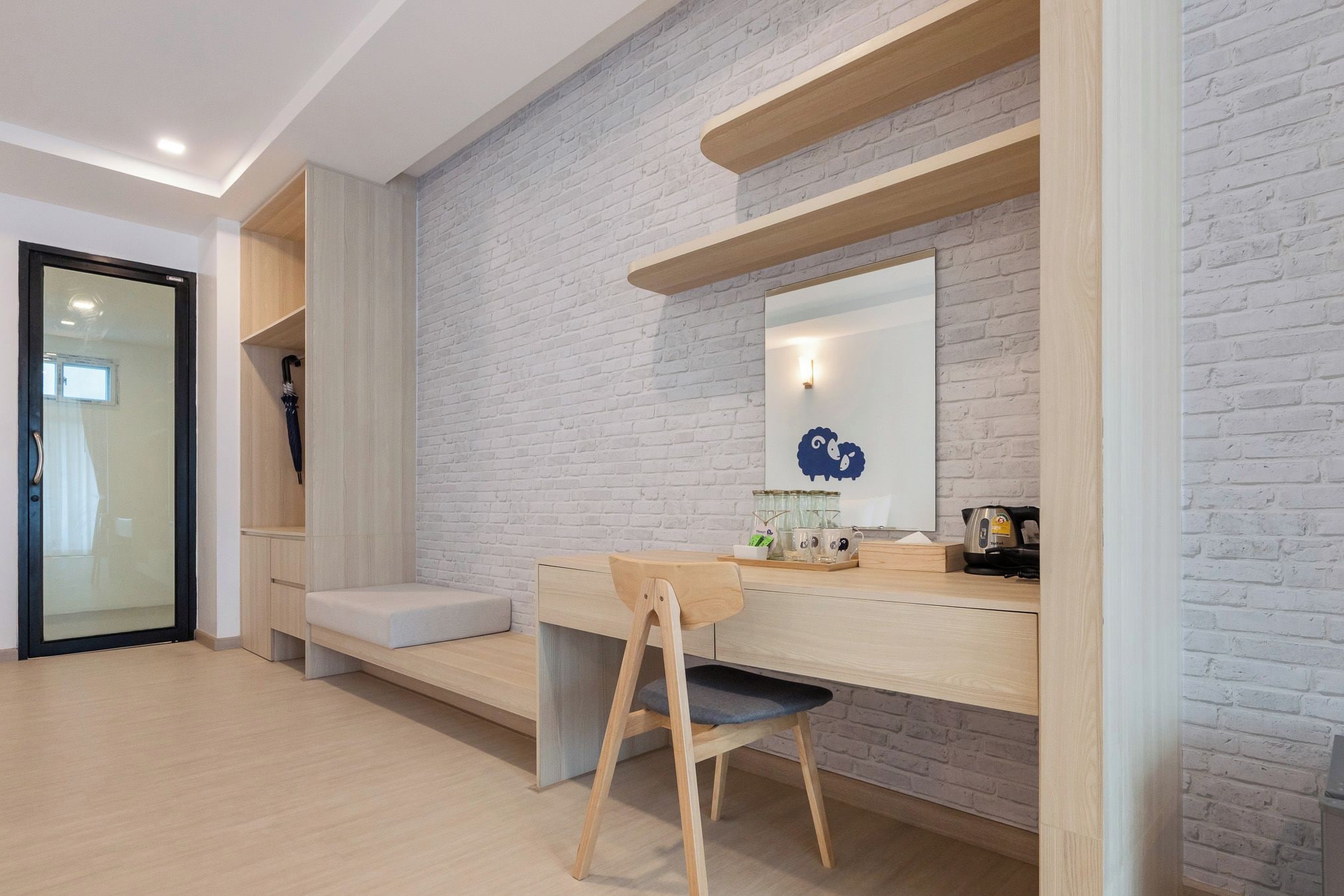 Une chambre moderne avec un bureau, une chaise et un mur en briques blanches.