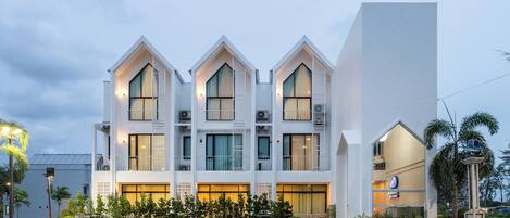 Un edificio moderno con fachada simétrica, varios balcones y techo plano.